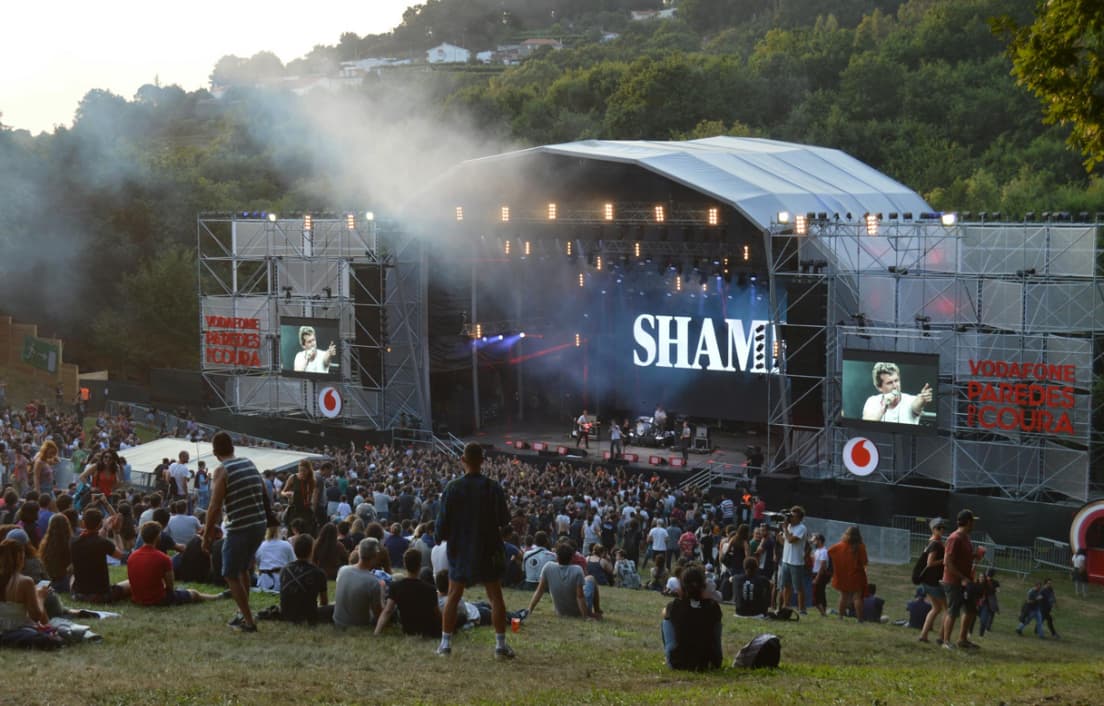 people sit on the grass on the hill and look at the stage