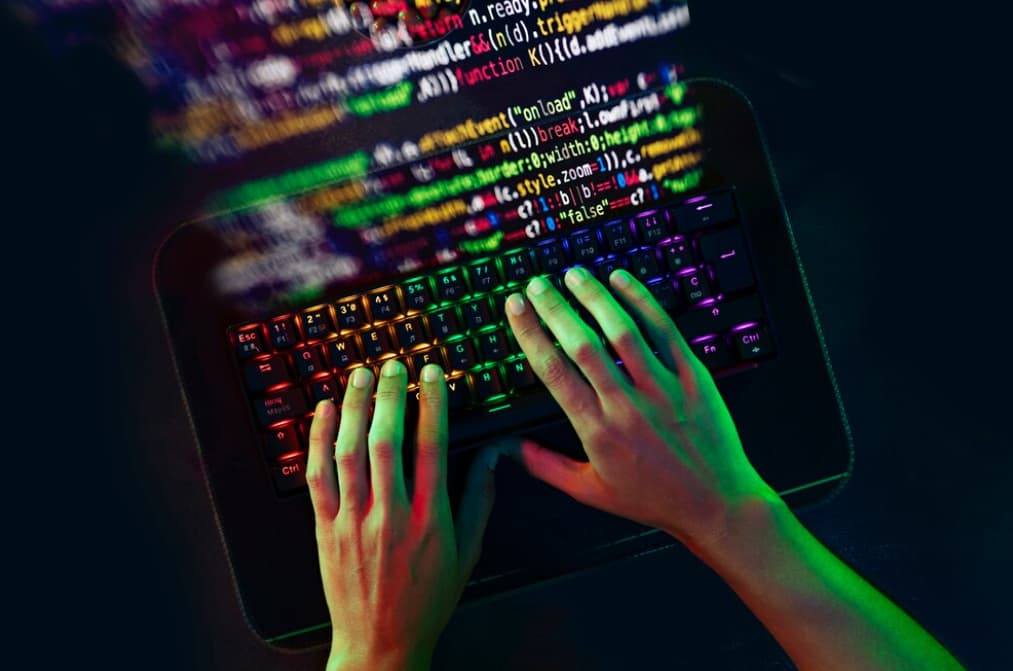 hands typing on the keyboard and colorful code above on black background