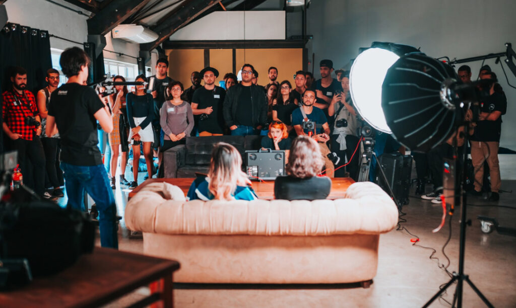A group of people watching a filming session, focused on a person with a camera