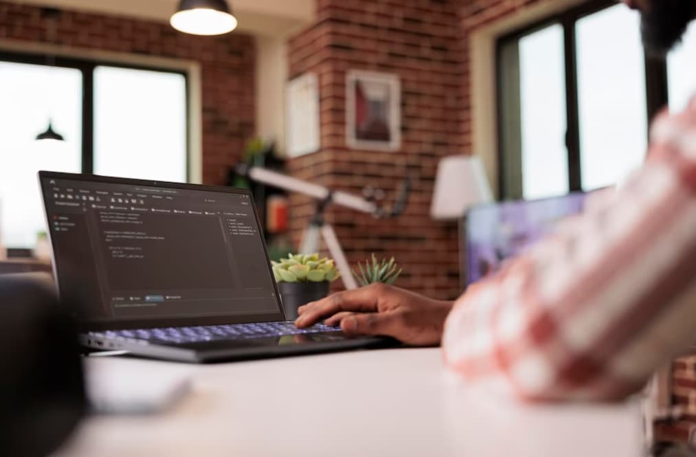 A person working on a laptop with code on the screen